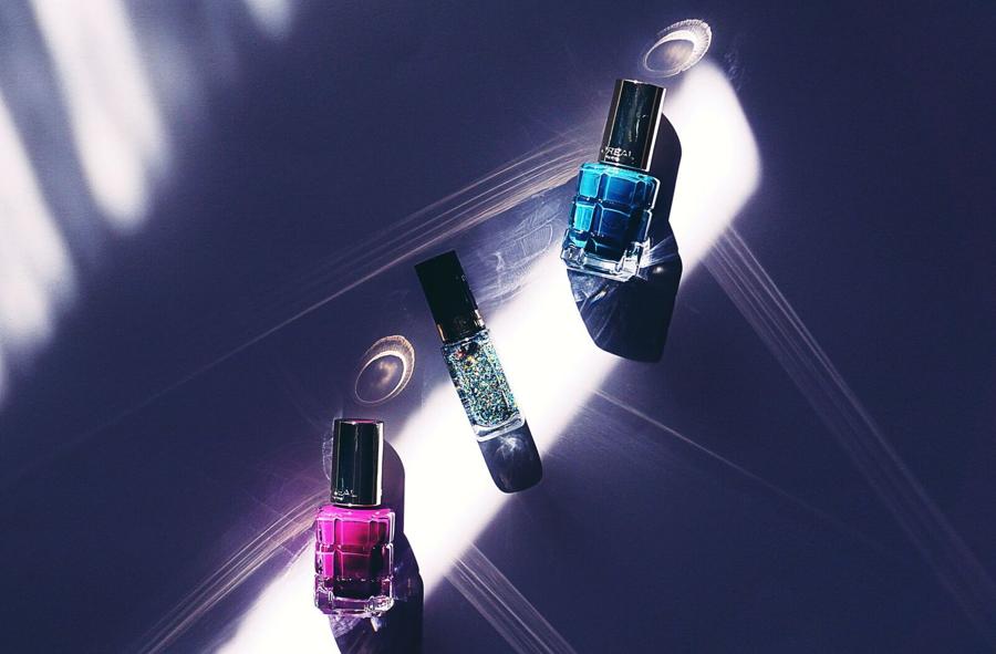 Three bottles of polish catching hard light on a dark counter